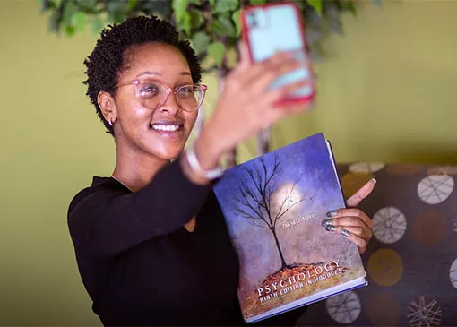 proud student takes selfie with textbook